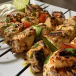 Primer plano de brochetas de pollo con aderezo de yogurt y rodajas de pepino.