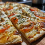 Vista lateral de una pizza de pollo con cebolla y jitomate.