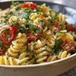 Un primer plano de pasta con espinacas, tomates cherry y queso feta.