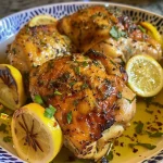 Pollo dorado con hierbas frescas y rodajas de limón.