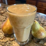 Batido de pera y jengibre en un vaso transparente.