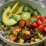 Un tazón de burrito vegano con tofu, quinoa y verduras frescas.