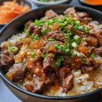 Donburi de carne con arroz blanco y huevo frito, presentado en un cuenco.