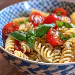 Nahaufnahme eines frischen Zitronen-Basilikum-Pasta-Salats mit bunten Kirschtomaten.