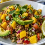 Ensalada de quinoa y mango con ingredientes frescos en un plato colorido.