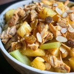 Ensalada de pollo y piña presentada en una hoja de lechuga, vista de lado.