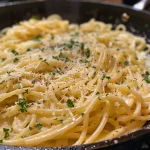 Close-up of creamy garlic pasta in a bowl, with parsley garnish.