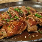 Pollo deshuesado glaseado con miel y miso, decorado con semillas de sésamo.