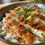 Close up de pollo glaseado junto a arroz japonés en un plato elegante.