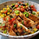 Vista lateral de un tazón de pollo Tex-Mex con ingredientes coloridos y vibrantemente presentados.