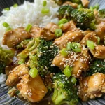 Imagen apetecible de pollo y brócoli salteados, presentados con semillas de sésamo.