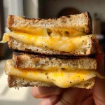 Sándwich de queso a la parrilla dorado con humeante queso derretido.