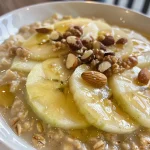['Tazón de gachas de avena con manzana y canela, decorado con rodajas de manzana.', 'Primer plano de avena cocida con manzana y canela, servida en un tazón.', 'Avena con manzana y canela lista para disfrutar, con ingredientes al fondo.', 'Gachas saludables de avena con trozos de manzana y espolvoreado de canela.']