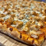 ['Pizza de pollo buffalo con pollo, queso y salsa picante.', 'Vista lateral de una pizza de pollo buffalo recién horneada.', 'Deliciosa pizza de pollo buffalo con ingredientes visibles.', 'Pizza de pollo buffalo lista para servir con ingredientes jugosos.']