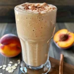 ['Smoothie de durazno en un vaso, con textura cremosa y decorado con canela.', 'Primer plano de un smoothie de durazno, con ingredientes visibles como el yogur y la canela.', 'Vaso de smoothie de durazno con un color vibrante y una pizca de canela encima.', 'Un refrescante smoothie de durazno servido en un vaso, ideal para el desayuno.']