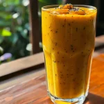 ['Smoothie de mango con cúrcuma y jengibre en un vaso.', 'Primer plano de un jugo de mango con fruta de la pasión y especias.', 'Vaso de smoothie de mango, cúrcuma y jengibre en detalle.', 'Bebida refrescante de mango y cúrcuma presentada en un vaso.']