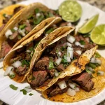 ['Tacos de bistec jugosos servidos con cebolla y cilantro.', 'Tacos de bistec coloridos con salsa verde y ingredientes frescos.', 'Primer plano de tacos de bistec en tortillas de maíz.', 'Tacos de bistec acompañados de vegetales y salsas.']