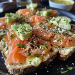 ['Tostas de salmón ahumado con aguacate sobre una tabla de madera.', 'Primer plano de tostas con salmón ahumado y rodajas de aguacate.', 'Tostas decoradas con salmón ahumado y aguacate en un plato.', 'Tostas de pan con salmón y aguacate, listas para servir.']