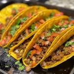 ['Tacos al horno de carne, dorados y crujientes, con queso derretido.', 'Primer plano de tacos de carne al horno, con toppings frescos.', 'Tacos horneados rellenos de carne y queso, listos para disfrutar.', 'Tacos crujientes de carne al horno, presentados en un plato.']