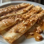 Crêpes con sirope de arce y nueces en un plato.